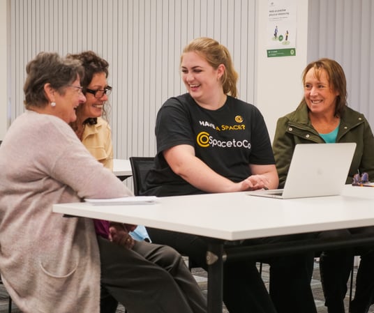 SpacetoCo team member demonstrating venue management software to community space managers on a laptop.