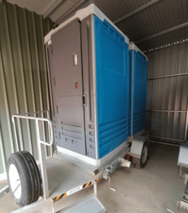 Trailer-mounted portable toilet unit parked inside a shed, available to hire through SpacetoCo