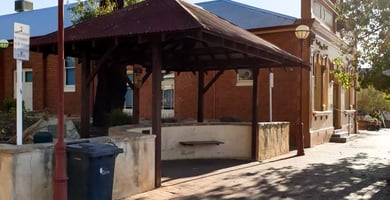 Timber-roofed outdoor shelter attached to a heritage red brick building, set up as a stall or workshop space, available to book on SpacetoCo