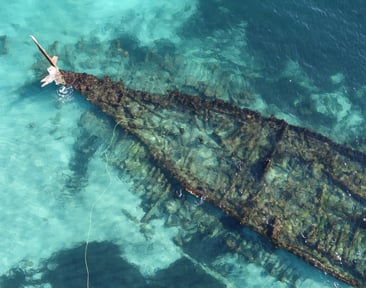 Aerial view of a shipwreck visible through clear turquoise water on the Coogee Maritime Trail, bookable on SpacetoCo