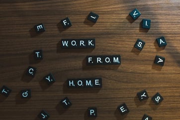 Scrabble tiles on a wooden table spelling out "work from hom